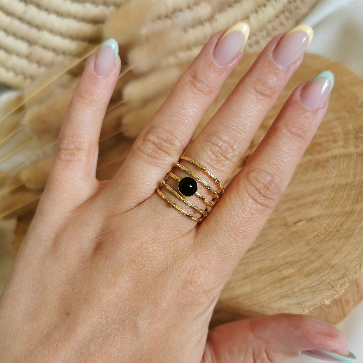 Une jolie bague en acier inoxydable doré avec plusieurs rangs et une pierre d'agate noire au centre