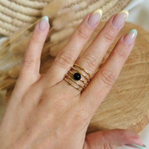 Une jolie bague en acier inoxydable doré avec plusieurs rangs et une pierre d'agate noire au centre