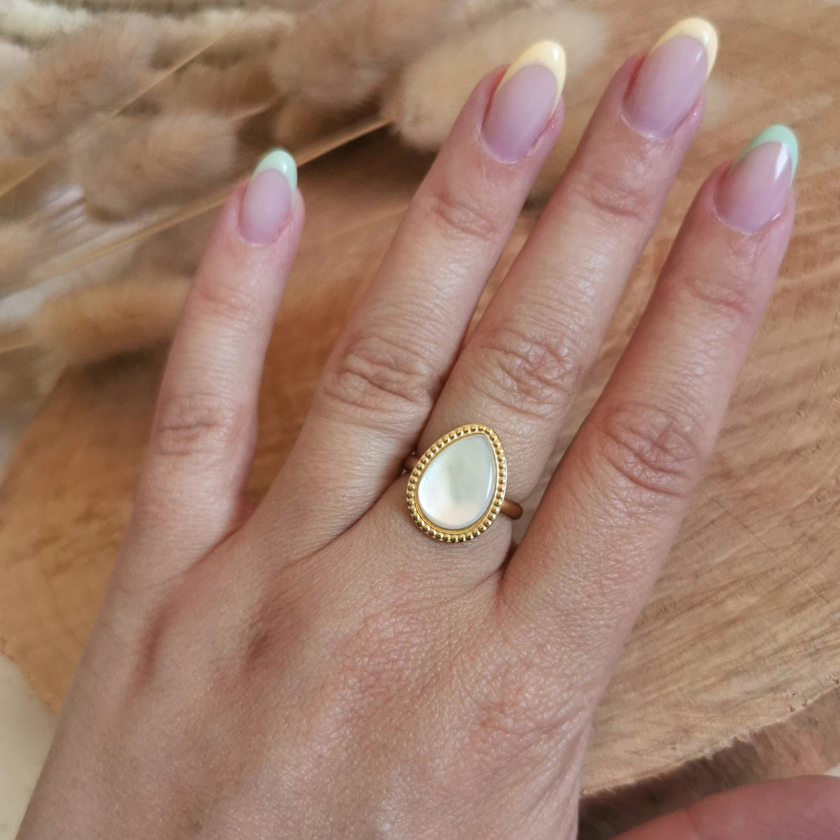 Une belle bague avec une jolie goutte avec une nacre sur de l'acier inoxydable doré
